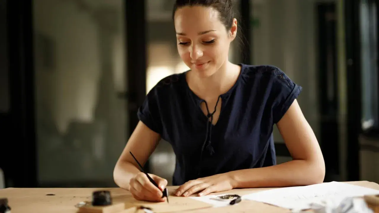 Donna scrive con una penna d'oca, ispirata a come scrivere una richiesta di lavoro esempio.