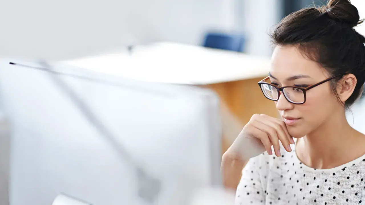Donna con occhiali, concentrata al computer, mentre prepara la sua autorizzazione al trattamento dei dati personali per il CV.