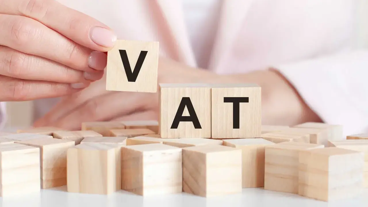 Dita che compongono la parola VAT con blocchi di legno. Un intestatario partita IVA che gioca con le lettere.