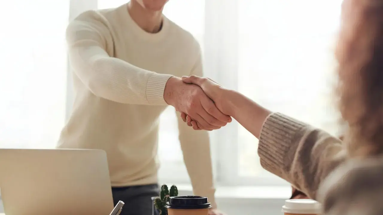 Due persone si stringono la mano, un gesto che può simboleggiare la conclusione di un rapporto lavorativo, il vero offboarding significato.
