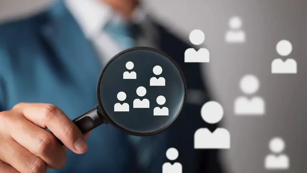 Un hiring manager esamina attentamente i candidati con una lente d'ingrandimento, cercando il talento giusto.