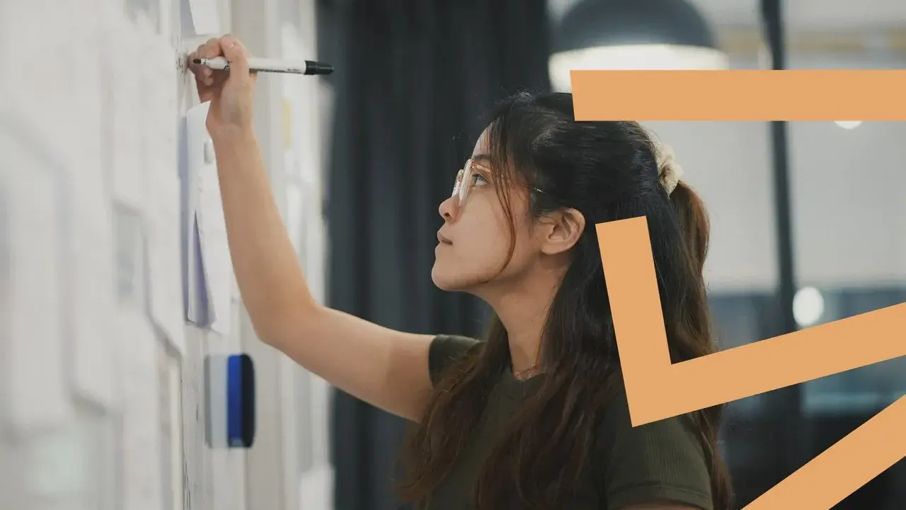 Donna con occhiali scrive su una lavagna. Il titolare di una ditta individuale può essere assunto come dipendente, esplorando nuove opportunità.