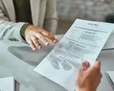 Mani che si passano un curriculum vitae. Un candidato presenta il suo cv, mostrando cosa scrivere per fare una buona impressione.