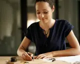 Donna scrive con una penna d'oca, ispirata a come scrivere una richiesta di lavoro esempio.