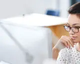 Donna con occhiali, concentrata al computer, mentre prepara la sua autorizzazione al trattamento dei dati personali per il CV.