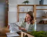 Agente immobiliare con partita IVA illustra una planimetria. L'ufficio è moderno e luminoso, con scaffali pieni di libri e oggetti decorativi.