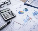 Occhiali, calcolatrice e grafici su fogli di calcolo, per un'analisi accurata del bilancio di competenza.