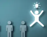 Una figura umana luminosa con una lampadina sopra la testa, simbolo di problem solving, si distingue da altre figure grigie.
