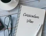 Taccuino con scritto "Curriculum Vitae", occhiali, smartphone e tazza di caffè. Preparazione per il curriculum trattamento dati.