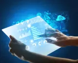 Hands holding a futuristic tablet displaying glowing data, charts, and a globe.