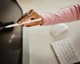 Mano con stilo bianco che interagisce con uno schermo, mentre sullo sfondo si intravedono tastiera e mouse. Ottimizzazione del cv per i sistemi ats.