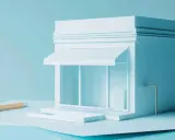 Un modello di negozio bianco su sfondo azzurro, con una matita e fogli. Quanti codici ATECO si possono avere per un'attività?