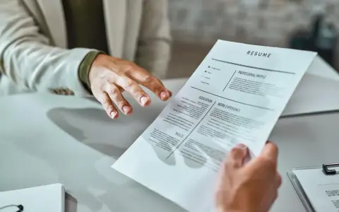 Mani che si passano un curriculum vitae. Un candidato presenta il suo cv, mostrando cosa scrivere per fare una buona impressione.