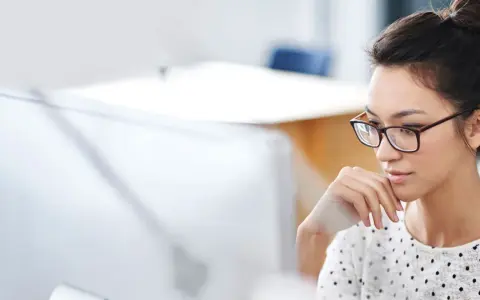 Donna con occhiali, concentrata al computer, mentre prepara la sua autorizzazione al trattamento dei dati personali per il CV.