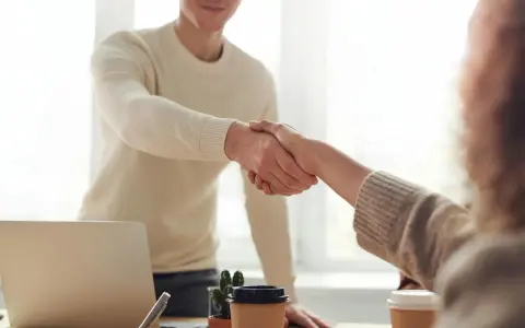 Due persone si stringono la mano, un gesto che può simboleggiare la conclusione di un rapporto lavorativo, il vero offboarding significato.