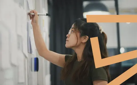 Donna con occhiali scrive su una lavagna. Il titolare di una ditta individuale può essere assunto come dipendente, esplorando nuove opportunità.