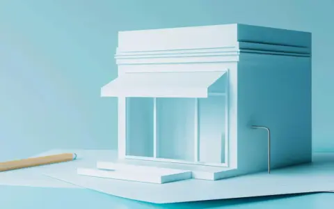 Un modello di negozio bianco su sfondo azzurro, con una matita e fogli. Quanti codici ATECO si possono avere per un'attività?