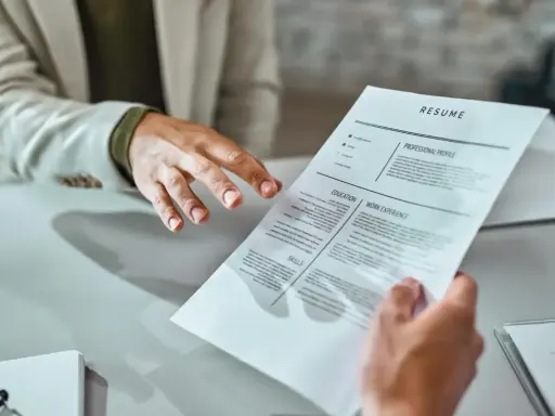 Mani che si passano un curriculum vitae. Un candidato presenta il suo cv, mostrando cosa scrivere per fare una buona impressione.