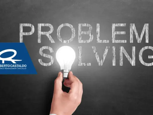 Una mano tiene una lampadina accesa, illuminando la parola "SOLVING" scritta sulla lavagna. Le parole "PROBLEM" e "SOLVING" suggeriscono l'importanza delle tecniche di problem solving.