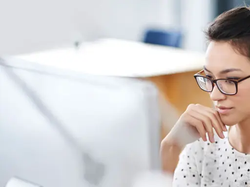 Donna con occhiali, concentrata al computer, mentre prepara la sua autorizzazione al trattamento dei dati personali per il CV.