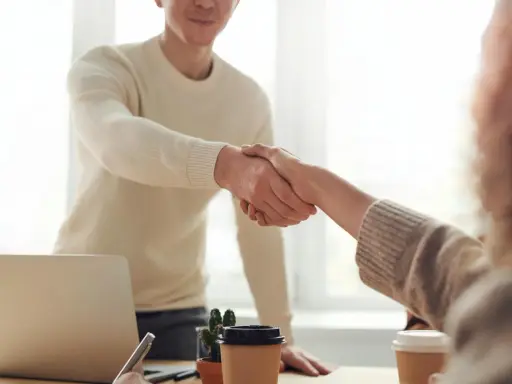 Due persone si stringono la mano, un gesto che può simboleggiare la conclusione di un rapporto lavorativo, il vero offboarding significato.