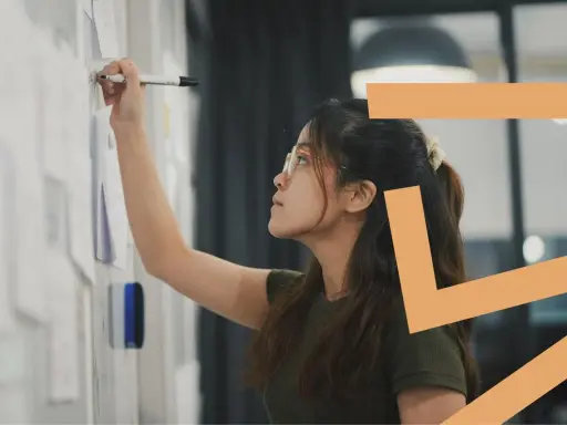 Donna con occhiali scrive su una lavagna. Il titolare di una ditta individuale può essere assunto come dipendente, esplorando nuove opportunità.