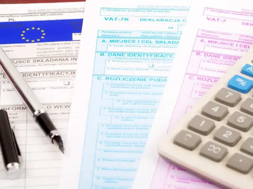 Documenti fiscali per il commercio auto usate regime forfettario. Penna e calcolatrice su moduli IVA.