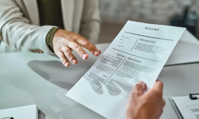 Mani che si passano un curriculum vitae. Un candidato presenta il suo cv, mostrando cosa scrivere per fare una buona impressione.