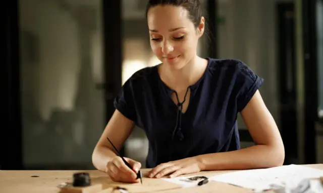 Donna scrive con una penna d'oca, ispirata a come scrivere una richiesta di lavoro esempio.