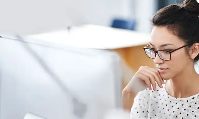 Donna con occhiali, concentrata al computer, mentre prepara la sua autorizzazione al trattamento dei dati personali per il CV.
