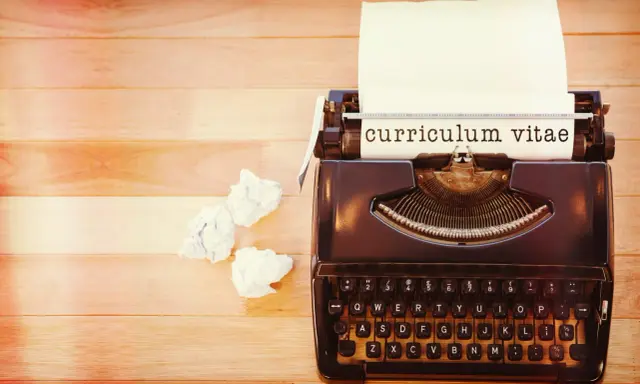 Macchina da scrivere con foglio su cui è scritto "curriculum vitae". Accanto, fogli accartocciati, simbolo di un cv cronologico in lavorazione.