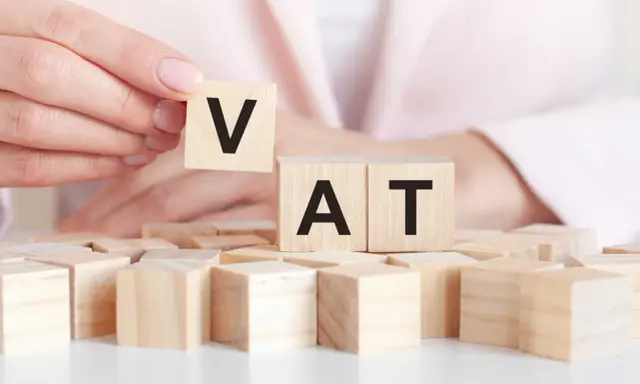 Dita che compongono la parola VAT con blocchi di legno. Un intestatario partita IVA che gioca con le lettere.