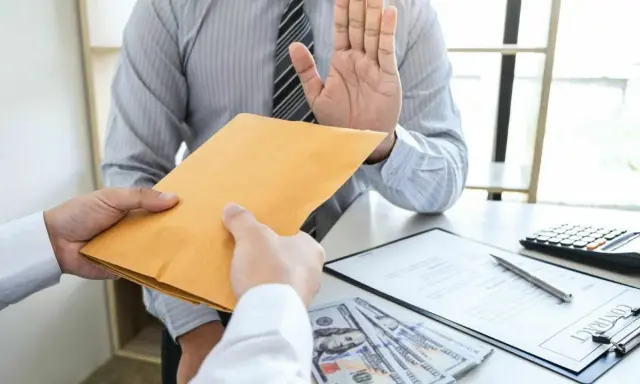 Uomo con mano alzata rifiuta busta marrone, mostrando come rifiutare una proposta di lavoro con integrità.