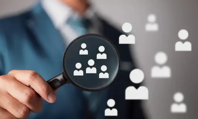 Un hiring manager esamina attentamente i candidati con una lente d'ingrandimento, cercando il talento giusto.