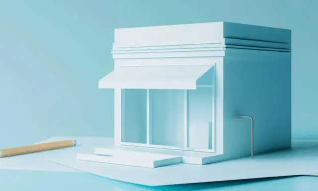 Un modello di negozio bianco su sfondo azzurro, con una matita e fogli. Quanti codici ATECO si possono avere per un'attività?