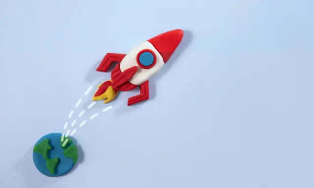 Un razzo di plastilina decolla dalla Terra, pronto per nuove avventure. La risposta a "perché vuoi lavorare con noi" è: per spiccare il volo verso il successo!