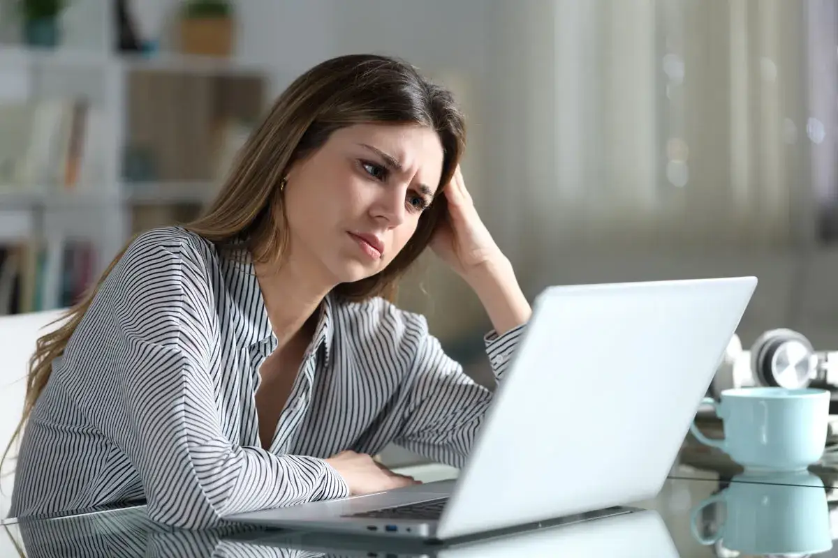 Donna pensierosa davanti al laptop, riflette su come rifiutare una proposta di lavoro.