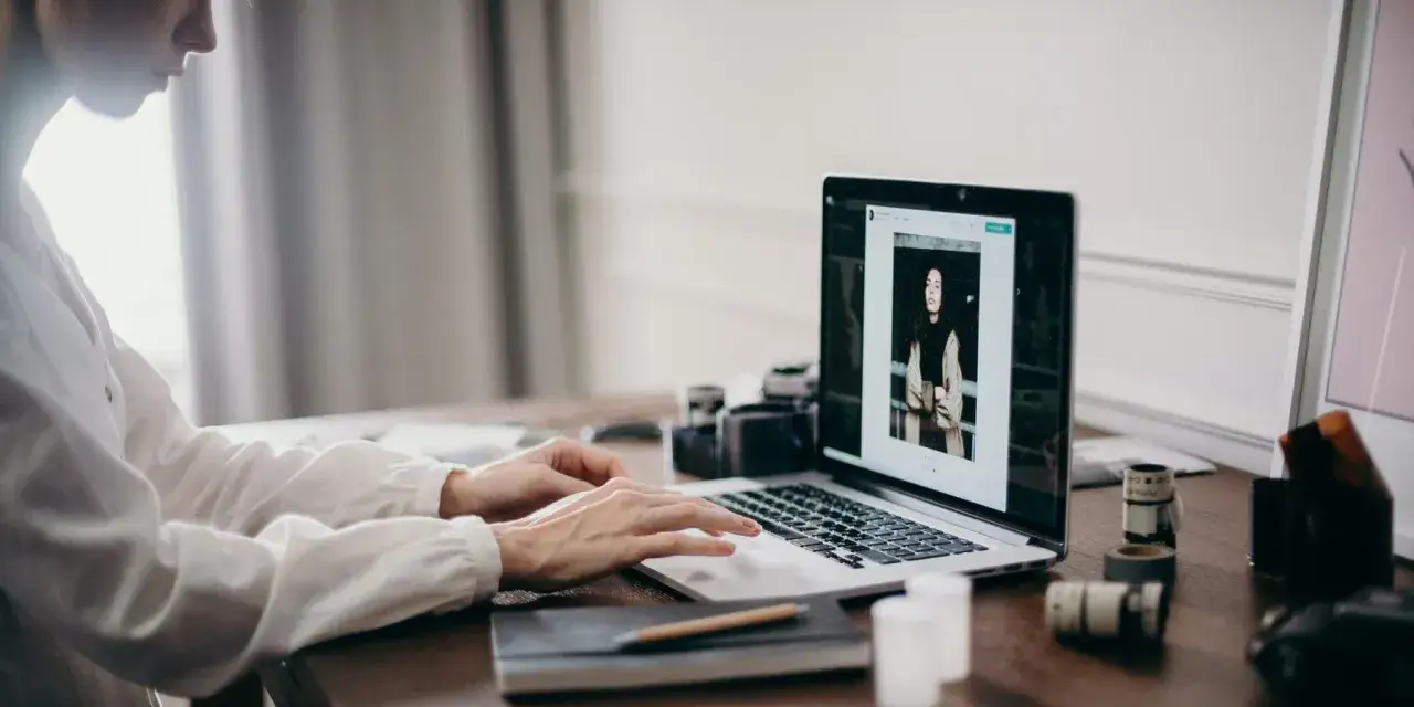 Woman typing on a laptop with a photo editing interface open.